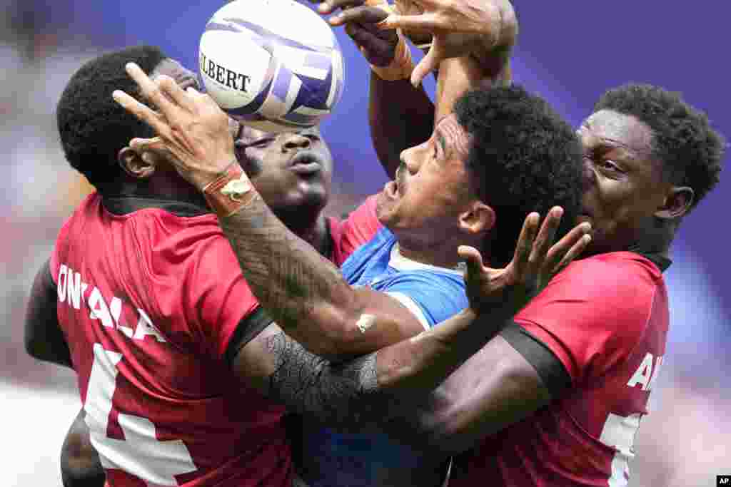 Samoa's Vaa Apelu Maliko retains the ball despite the efforts of Kenya's Vincent Onyala, left and Kenya's Nygel Pettersan Amaitsa, during the men's Rugby Sevens Pool B match between Samoa and Kenya, at the 2024 Summer Olympics, in the Stade de France, in Saint-Denis, France.