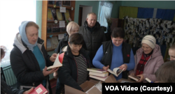 Мешканці села Стодульці на Вінничині розглядають нові книги, які їм надіслали волонтери зі США