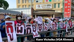 ក្រុមបុគ្គលិក និងសហជីពណាហ្គាវើលដ៍ ឈរលើកបដា និងរូបថត គាំទ្រថ្នាក់ដឹកនាំសហជីពរបស់ខ្លួន នៅខឿនផ្លូវម្ខាងទៀតពីមុខតុលាការ នៅថ្ងៃទី២៥ ខែឧសភា ឆ្នាំ២០២៣។ (កាន់ វិច្ឆិកា/វីអូអេ)