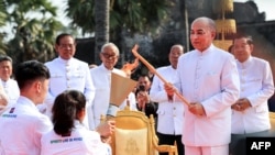 ព្រះមហាក្សត្រ​នរោត្តម សហមុនី ​​ប្រោស​ព្រះរាជ​ទាន​ព្រះ​អគ្គិ​ជ័យ​​នៅពេល​ដែល​នាយករដ្ឋមន្ត្រី​ហ៊ុន សែន​មើលពីក្រោយ។(Ja Dina / AFP)