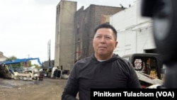 สัมฤทธิ์ ขณะให้สัมภาษณ์ โกดังสีขาวด้านหลังคือโกดังหลังแรกของธุรกิจ