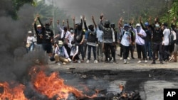 រូបឯកសារ៖ ក្រុមបាតុករប្រឆាំងរដ្ឋប្រហារធ្វើកាយវិការដោយលើកម្រាបដៃបីគោរព ដែលជានិមិត្តរូបនៃការតស៊ូប្រឆាំងនឹងរបបយោធា ក្នុងអំឡុងការបង្រ្កាបរបស់ប៉ូលិសក្នុងសង្កាត់ Thaketa ក្រុង Yangon ប្រទេសមីយ៉ាន់ម៉ា ថ្ងៃទី២៧ ខែមីនា ឆ្នាំ២០២១។