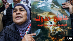 مغربی کنارے کی ایک خاتون بینر کے ذریعے فلسطینیوں کی مصنوعات کے فروغ اور اسرائیلی مصنوعات کے بائیکاٹ کی مہم چلا رہی ہے۔ فوٹو اے ایف پی