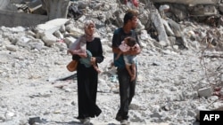 Պաղեստինցի զույգը իրենց երեխաների հետ միասին, երբ նրանք քայլում են բեկորների միջով Գազայի հատվածի հարավում գտնվող Խան Յունիսում 2024 թվականի հուլիսի 4-ին