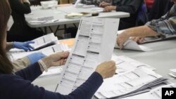 FILE - An election worker examines a ballot on May 19, 2022, in Oregon City, Ore. 