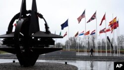 Seorang pria berjalan melintas di depan bendera negara-negara anggota Pakta Pertahanan Atlantik Utara (NATO) di markas NATO di Brussels, Belgia, 11 Maret 2024. (Foto: Geert Vanden Wijngaert/AP Photo)