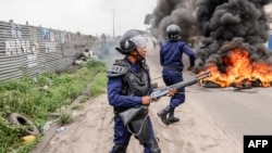 2023 年 12 月 27 日，金沙萨反对派示威期间，刚果民主共和国警察站在燃烧的路障旁。