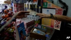 El encargado de un comercio en Caracas entrega cambio en dólares estadounidenses a un cliente, el 13 de mayo de 2022.