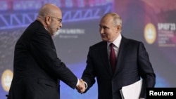 俄羅斯總統普京在聖彼得堡國際經濟論壇的會議中與主持人德米特里·西姆斯握手。 (2023年6月16日)