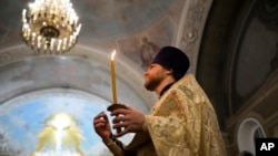 A Russian Orthodox Church priest makes the sign of the cross during an Orthodox Christmas service at the Church of the Holy Martyr Tatiana near the Kremlin Wall in Moscow, Jan. 6, 2024. 