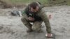 Seorang tentara pencari ranjau tampak mengambil serpihan bom tandan yang gagal meledak di area dekat desa Motyzhyn, di Kyiv, Ukraina, pada 10 April 2022. (Foto: Reuters/Mykola Tymchenko)