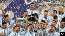 El argentino Lionel Messi, centro, sostiene el trofeo mientras celebra con sus compañeros tras vencer 1-0 a Brasil en la final de la Copa América en el estadio Maracaná de Río de Janeiro, Brasil, el sábado 10 de julio de 2021. (AP Foto/Andre Penner)