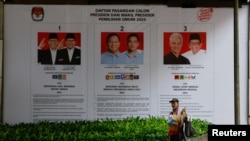 រូបឯកសារ៖ បុរសម្នាក់​ដើរ​កាត់​បដាដ៏ធំមួួយ​ដែល​បង្ហាញ​បេក្ខជន​ប្រធានាធិបតី​សម្រាប់​ការ​បោះឆ្នោត​ជាតិ​នាពេលខាងមុខ នៅរដ្ឋធានី​ហ្សាការតា ប្រទេស​ឥណ្ឌូណេស៊ី កាលពីថ្ងៃទី១២ ខែមករា ឆ្នាំ២០២៤។ 