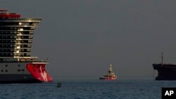 Brod koji pripada grupi za pomoć Open Arms, centar, jedan od tri broda natovarena konzerviranom hranom namijenjenoj Gazi, isplovljava iz kiparske luke dok se francuski ratni brod vidi s desne strane, u Larnaki, Kipar, 30. marta 2024.