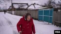 Una mujer camina sobre la nieve en Nova Kozacha, Ucrania, el 14 de febrero de 2023. Esta pequeña aldea fronteriza ha perdido más del 75 % de su población desde el comienzo de la guerra. Pocas personas han regresado, muchos temen que Rusia vuelva a atacar. [Foto: Yan Boechat, VOA]