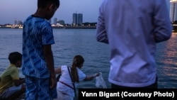 ស្រ្តីម្នាក់ព្រលែងត្រី ដែលជាសត្វគេនិយមព្រលែងដូចសត្វចាបនិងសត្វដទៃទៀត ចូលទៅក្នុងចំណុចប្រសព្វគ្នារវាងទន្លេសាប និងទន្លេមេគង្គ នៅថ្ងៃវិសាខបូជា។ (រូបផ្តល់ឱ្យដោយលោក Yann Bigant)