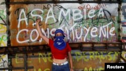 ARCHIVO - Un manifestante posa para un retrato frente a un grafiti que dice "Asamblea Constituyente" durante una protesta contra el gobierno de Chile en Santiago de Chile, en noviembre de 2019.
