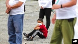 Un joven se sienta en medio de excombatientes de las FARC para una ceremonia en la que los exguerrilleros se disculparon con los lugareños por los secuestros perpetrados por las FARC durante décadas en la zona rural de Pipiral , Colombia, el 29 de octubre de 2020.