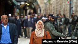 Una mujer musulmana camina por la ciudad Vieja de Jerusalén, fuertemente custodiada por policías israelíes durante el primer viernes del mes sagrado del Ramadán.