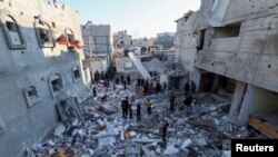 Palestinos inspeccionan los escombros dejados por misil israelí que impactó contra viviendas en Rafah, en la franja de Gaza, el 29 de diciembre, en la ofensiva de Israel contra Hamás.