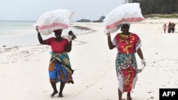 Watu waliojitolea wakiwa wamebeba mifuko iliyojaa uchafu wa plastiki katika kaunti ya Kilifi, Kenya. Picha na Simon MAINA / AFP. 