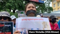 ក្រុមបុគ្គលិក និងសហជីពណាហ្គាវើលដ៍ ឈរលើកបដា និងរូបថត គាំទ្រថ្នាក់ដឹកនាំសហជីពរបស់ខ្លួន នៅខឿនផ្លូវម្ខាងទៀតពីមុខតុលាការ នៅថ្ងៃទី២៥ ខែឧសភា ឆ្នាំ២០២៣។ (កាន់ វិច្ឆិកា/វីអូអេ)