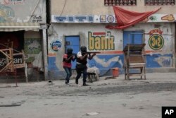 Petugas polisi berlindung selama operasi anti-geng di lingkungan Portail Port-au-Prince, Haiti, Selasa, 25 April 2023 (Foto: AP)