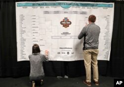 FILE - Staff members for the NCAA place the names of the teams in the Sweet 16 on a bracket in the media workroom before practices at the East Regional of the NCAA college basketball tournament in New York, March 23, 2017. (AP Photo/Julie Jacobson, File)