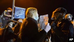 在北亚利桑那大学，一名支持巴勒斯坦人的抗议者举着标语与警察对峙。(2024年4月30日)