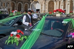An Afghan groom stands next to decorated cars outside a wedding hall during the mass wedding ceremony in Kabul, Dec. 25, 2023.
