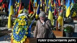 A visitor walks through the military section of Lychakiv cemetery in Lviv, Ukraine, March 18, 2023.