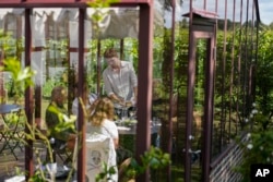 A waiter pours wine during a tasting with the vineyard in the background, at Kullabergs Vingård, in Nyhamnsläge, Sweden, July 25, 2023.