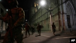 Soldiers walk towards a vehicle that blew up outside the Women´s and Human Rights Ministry building in Quito, Ecuador, Aug. 30, 2023.