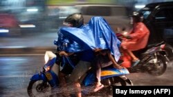 Pengendara motor mengenakan jas hujan saat berkendara saat hujan deras mengguyur Ibu Kota Jakarta pada 19 Januari 2022. (Foto: BAY ISMOYO/AFP)