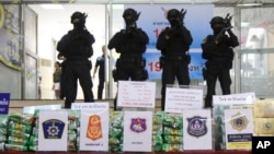 FILE - Thai policemen stand in front of packages of methamphetamines on display during a press conference at the Narcotics Suppression Bureau in Bangkok, Thailand, July 15, 2019.
