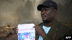 Jacob Inje akiwa na picha ya mpwa wake akisubiri kutoa sampuli ya DNA huko Malindi, tarehe 1 Mei 2023. Picha na SIMON MAINA / AFP. 