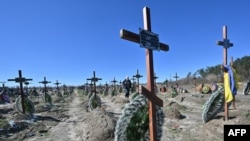 Un hombre camina entre las tumbas de personas locales no identificadas que fueron asesinadas en la ciudad ucraniana de Bucha, al noroeste de Kiev, un día antes de la celebración del primer aniversario de la liberación de Bucha de las tropas rusas el 31 de marzo.