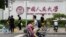 北京街頭人們經過中國人民大學校園外牆的標識。（2024年7月22日）
