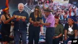 Brazil's President Luiz Inacio Lula da Silva receives gifts from Indigenous leaders at the Caracarana Lake Regional Center in Roraima state, Brazil, Monday, March 13, 2023. (AP Photo/Edmar Barros)