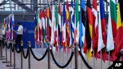A man moves flags of European Union countries as he prepares for an upcoming EU summit at the European Council building in Brussels, March 20, 2024. 