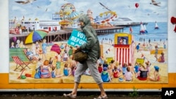 Žena prolazi pored plakata Reformske stranke Nigela Faragea (Foto: AP/Vadim Ghirda)