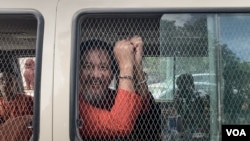 រូបឯកសារ៖ លោក ថាច់ សេដ្ឋា អនុប្រធានគណបក្សភ្លើងទៀន បង្ហាញខ្នោះដៃពីក្នុងឡាន នៅពេលលោកត្រូវបានដឹកចេញពីតុលាការកំពូលទៅពន្ធនាគារព្រៃស កាលពីថ្ងៃទី១៩ ខែមិថុនា ឆ្នាំ២០២៣។ (លាស់ លីបលីប/វីអូអេ)