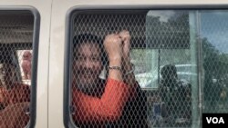 រូប​ឯកសារ៖ លោក ថាច់ សេដ្ឋា អនុប្រធានគណបក្សភ្លើងទៀន បង្ហាញខ្នោះដៃពីក្នុងឡាន នៅពេលលោកត្រូវបានដឹកចេញពីតុលាការកំពូលទៅពន្ធនាគារព្រៃស កាលពីថ្ងៃទី១៩ ខែមិថុនា ឆ្នាំ២០២៣។ (លាស់ លីបលីប/វីអូអេ)