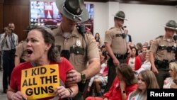 Authorities remove Allison Polidor (left) from a House Civil Justice Hearing for holding a sign during a legislative session in Nashville, Tennessee, to discuss gun violence, Aug. 22, 2023.