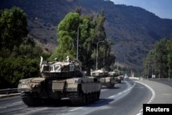 Un convoy de vehículos militares israelíes viaja por una carretera cerca de la frontera de Israel con el Líbano en el norte de Israel, el 8 de octubre de 2023.