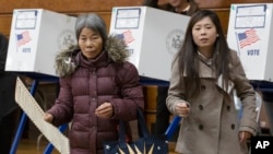 Seorang pemilih (kiri), membawa surat suaranya, sambil dibantu oleh penerjemah Ping Chan, di lingkungan Sunset Park wilayah Brooklyn, New York, Selasa, 8 November 2016. (AP/Mark Lennihan)