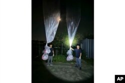 Pembelot Korea Utara Park Sang-hak (kiri) dan anggota Fighters For A Free North Korea memegang balon bertuliskan selebaran propaganda anti-Korea Utara di Paju, Korea Selatan, dekat perbatasan dengan Korea Utara, Kamis, 20 Juni 2024. (Pejuang Untuk Korea Utara yang Merdeka via AP)