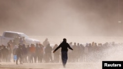 2023年4月25日，從墨西哥華雷斯城看到的移民在越過布拉沃河後，站在邊境牆附近，打算向美國邊境巡邏隊特工自首。（路透社照片）