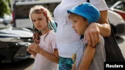 10-річна Ангеліна та 9-річний Олександр возз'єднані зі своєю матір'ю Світланою після повернення з окупованої території України, 6 вересня 2023. За даними Києва, до Росії було депортовано понад 19 500 дітей. Повернути вдалось лише близько 400 дітей. REUTERS/Gleb Garanich