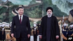 In this photo released by Xinhua News Agency, visiting Iranian President Ebrahim Raisi, right, walks with Chinese President Xi Jinping after reviewing an honor guard during a welcome ceremony at the Great Hall of the People in Beijing, Feb. 14, 2023